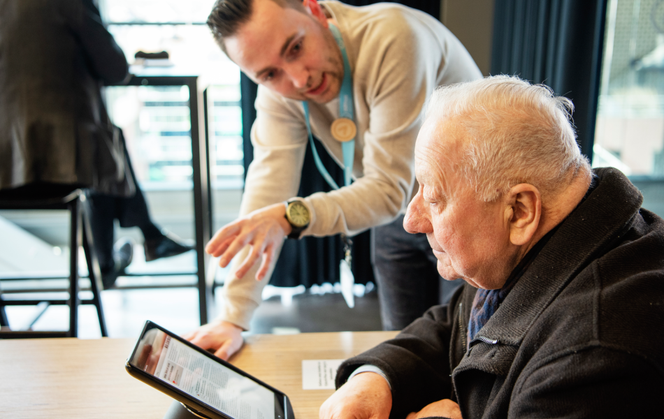 ARhus-medewerker geeft uitleg over tablet aan oudere man