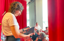 Vrouw kijkt in boek met rode gordijnen op de achtergrond