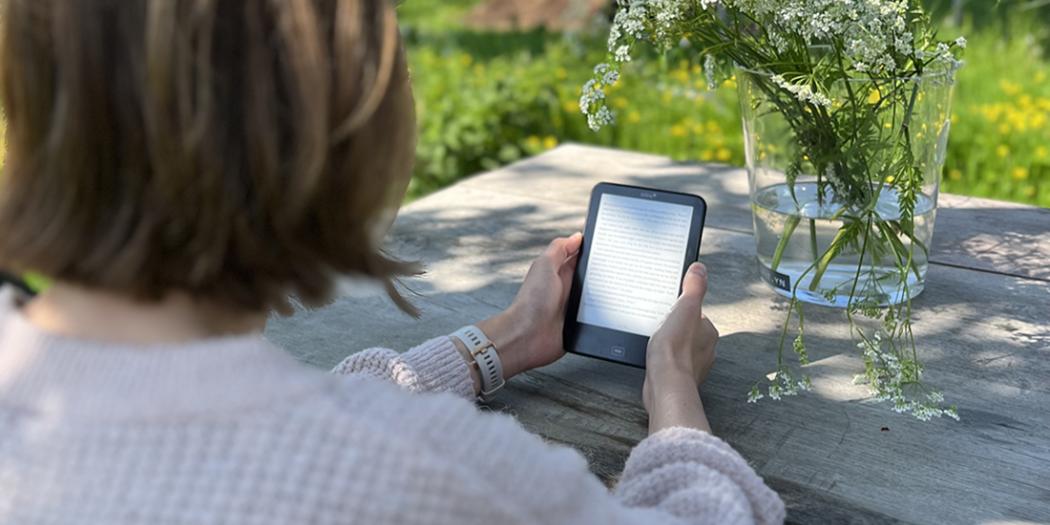 Vrouw leest e-boek in de tuin