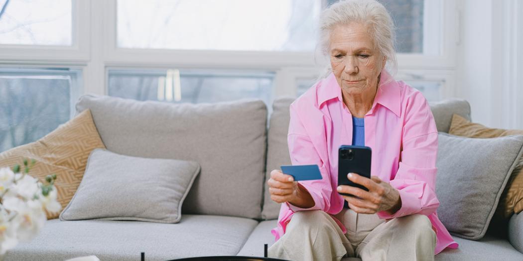 Digitale erfenis Senior met bankkaart en smartphone in de hand