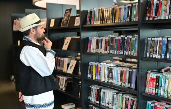 Man met hoedje kijkt naar boekenrek