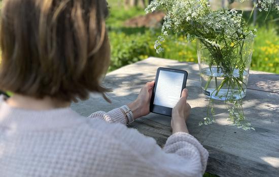 Vrouw leest e-boek in de tuin
