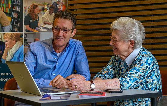 Digihelper legt senior uit hoe laptop werkt